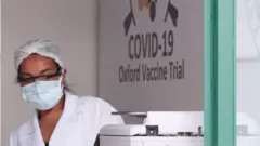 Profissional de saúde com logo da pesquisa de Oxford atrás