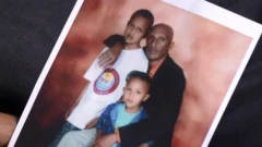 Moti Dereje con una vieja fotografía familiar de él y su hermano menor cuando eran niños con su padre.