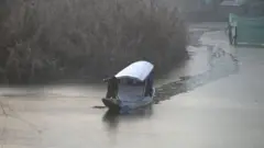 কাশ্মীরে জমাট বাঁধা লেকে নৌকা।