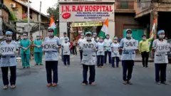 Medical staff members hold placards as they stand outside a hospital to show solidarity with people who are affected by the coronavirus disease (COVID-19), and with doctors, nurses and other healthcare workers from all over the world during a 21-day nationwide lockdown to slow the spreading of the disease, in Kolkata, India, April 5, 2020.