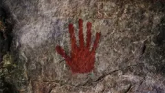 A red handprint on a cave wall.