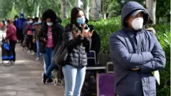 Cola de personas con mascarilla y carritos para llevar alimentos en Madrid