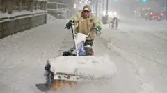 A man clears snow as snow falls near Bryant park during a Nor"easter, during the coronavirus disease (COVID-19) pandemic in the Manhattan borough of New York City, New York, US on 16 December 2020
