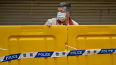 A man stands behind barriers during lockdown as a measure against the Covid-19 coronavirus in Shanghai.