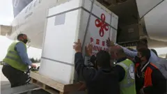 عمال ينزلون صناديق تحوي لقاح سينوفارم الصيني من إحدى الطائرات في مطار دمشق الدولي تبرعت بها الصين لسوريا
