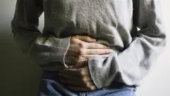Una mujer se toca el abdomen, debido al dolor