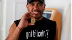 El entusiasta de Bitcoin Carlos Bonilla muestra una representación física de la criptomoneda, en una oficina de soporte de Bitcoin Beach en El Zonte Beach en Chiltiupán, El Salvador.
