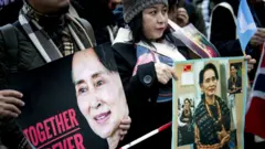 ဒေါ်အောင်ဆန်းစုကြည်နဲ့ အတူရပ်တည်ပါတယ်ဆိုတဲ့ ဆိုင်းဘုတ်တွေကိုင်ပြီး ဝန်းရံခဲ့ကြ