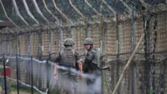 South Korean soldiers patrol along a fence in the Demilitarized zone
