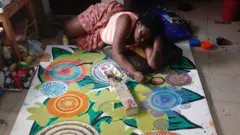 Ijeoma Ogwuegbu allongée sur le sol, en train de peindre.