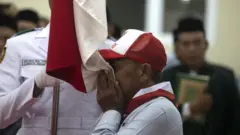 Perwakilan dari mantan anggota Negara Islam Indonesia (NII) mencium bendera Merah Putih saat acara cabut baiat massal mantan anggota Negara Islam Indonesia di Asrama Haji Kabupaten Indramayu, Jawa Barat, Rabu (16/8/2023). Sebanyak 121 orang mantan pengikut NII melakukan sumpah setia kepada Negara Kesatuan Republik Indonesia (NKRI).