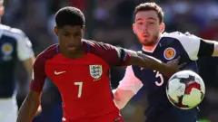 Marcus Rashford and Andrew Robertson compete for possession during Scotland v England in June 2017