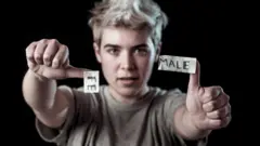 Adolescente transgénero desgarrando la palabra Female en MALE.