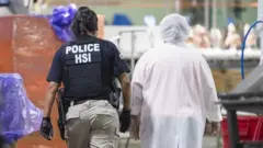 Una agente del Departamento de Investigaciones de Seguridad Nacional de Estados Unidos con una persona trabajadora de una planta procesadora en Misisipi
