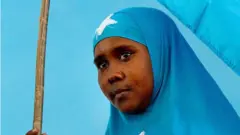 A Somali woman holds the national flag during a ceremony marking President Sheikh Sharif Sheikh Ahem's first year in office at the Villa Somalia presidential palace in Mogadishu on January 29, 2010