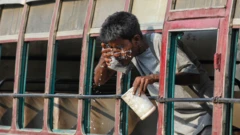 A man washes his face through the window of a bus amidst summer heatwave in Kolkata