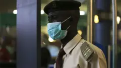Immigration officer wey wear face mask for Nnamdi Azikiwe International Airport in Abuja, August 11, 2014 wey Nigeria dey battle Ebola.