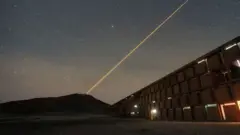 Un haz luminoso se eleva hacia el cielo estrellado en el edificio para científicos de Chile.