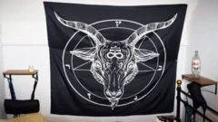 Um tecido preto está pendurado na parede com uma imagem satânica em branco.