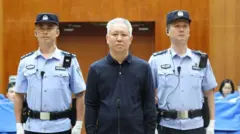 許家印（中）在法警押送下，於中國廣東深圳市中級法院出庭（深圳中級法院圖片20/8/2026）