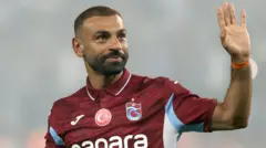 محمد صلاح يرفع يديه ويرتدي قميص نادي طرابزون التركي لكرة القدم