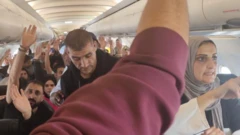 Палестинцы в салоне самолета, большинство - с поднятой рукой