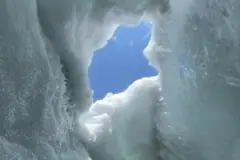 Um buraco na neve, com o céu azul ao fundo