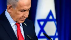 Netanyahu kürsüde önüne bakıyor, ger,de İsrail bayrağı var. 