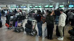 Очереди из людей с тележками с багажом ждут в оживленном терминале аэропорта