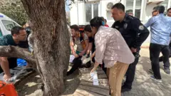 Окупљени људи испред школе указују помоћ повређеном ученику