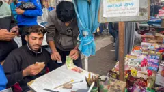 Baraa Abu Aoun repairs banknotes in a market in Gaza City