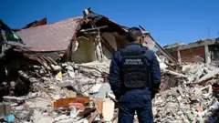 Policía frente a una casa derruida en El Junquito.