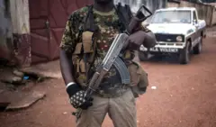An armed militiaman, stands guard at the entrance of the headquarters of the Muslim "self-defence force" group of the PK5 majority Muslim district of Bangui, on November 15, 2017