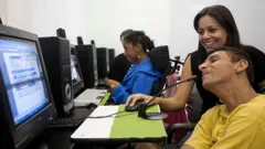 Uma pessoa com deficiência em uma mesa com um computador.