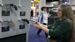 Mulher manuseia uma pistola Taurus durante reunião anual da Associação Nacional de Rifles da América, em 26 de abril de 2025, em Atlanta, Geórgia