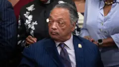 Джесси Джексон в пиджаке и галстуке.