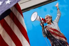 Uma mulher com um megafone na boca e usando uma bandeira dos EUA no corpo