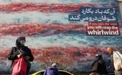iran i amerika, iranci prolaze pored velikog bilborda na kojem piše: Ako pošalješ vetar, požnjećeš vihor