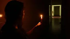 شخص يحمل شمعة بعد استمرار انقطاع الكهرباء في البرتغال وإسبانيا ليل الإثنين