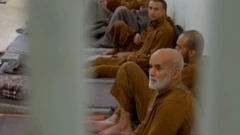 چند زندانی با لباس نارنجی در سلول عمومی