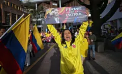 Una mujer vestida con ropa de la selección de fútbol colombiana sostiene un cartel de la campaña de Abelardo de la Espriella con su imagen y el eslógan "Firme por la patria" en Bogotá el 12 de junio de 2026.