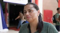 Marluize Avila, mulher de pee morena e cabelo liso, ao fundo a entrada do prédio