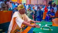 Nigeria President Bola Tinubu lay hands on two bags at the National Assembly