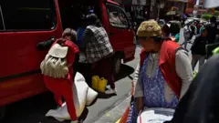 Mujeres bolivianas cargan víveres en una furgoneta en un mercado local en La Paz el 18 de diciembre de 2025.