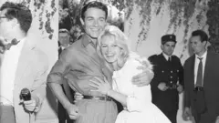 Brigitte Bardot, de 23 años, recibe un abrazo de su nuevo esposo, el actor Jacques Charrier, también de 23 años, tras su boda aquí, el 18 de junio.