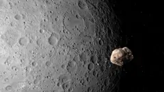 Ilustración de un asteroide cerca de la Luna. El asteroide brilla con un tono dorado al acercarse a la masa grisácea mucho más grande de la Luna.