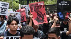Pengunjuk rasa memegang poster saat aksi di depan pintu gerbang Pancasila, Gedung DPR, Jakarta, Kamis (20/3/2025)