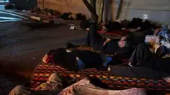  شب‌هنگام، تعداد زیادی از متقاضیان ویزا درمقابل درب سفارت چین در تهران روی زمین خوابیده‌اند