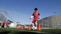 Crianças palestinas praticam futebol no campo construído em 2020, no campo de refugiados de Aida, Belém, no sul da Cisjordânia. O campo oferece uma área de lazer e esportes para muitas crianças e segue em funcionamento apesar da ameaça de demolição por parte das forças israelenses, em 16 de janeiro de 2026