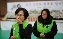 Muan, Güney Kore'de yakınlarını kazada kaybedenlerin üzüntüsü, iki kadın yeşil yelek giymiş. Biri ağlıyor.